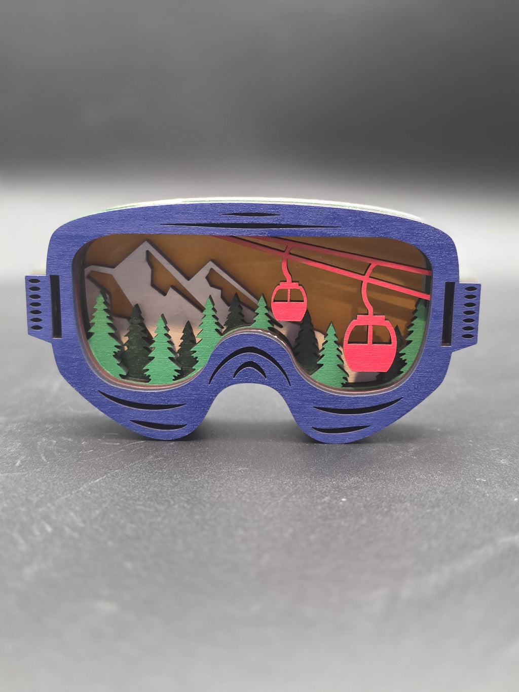 Blue-framed ski lift ornament with brown mountains and a red gondola