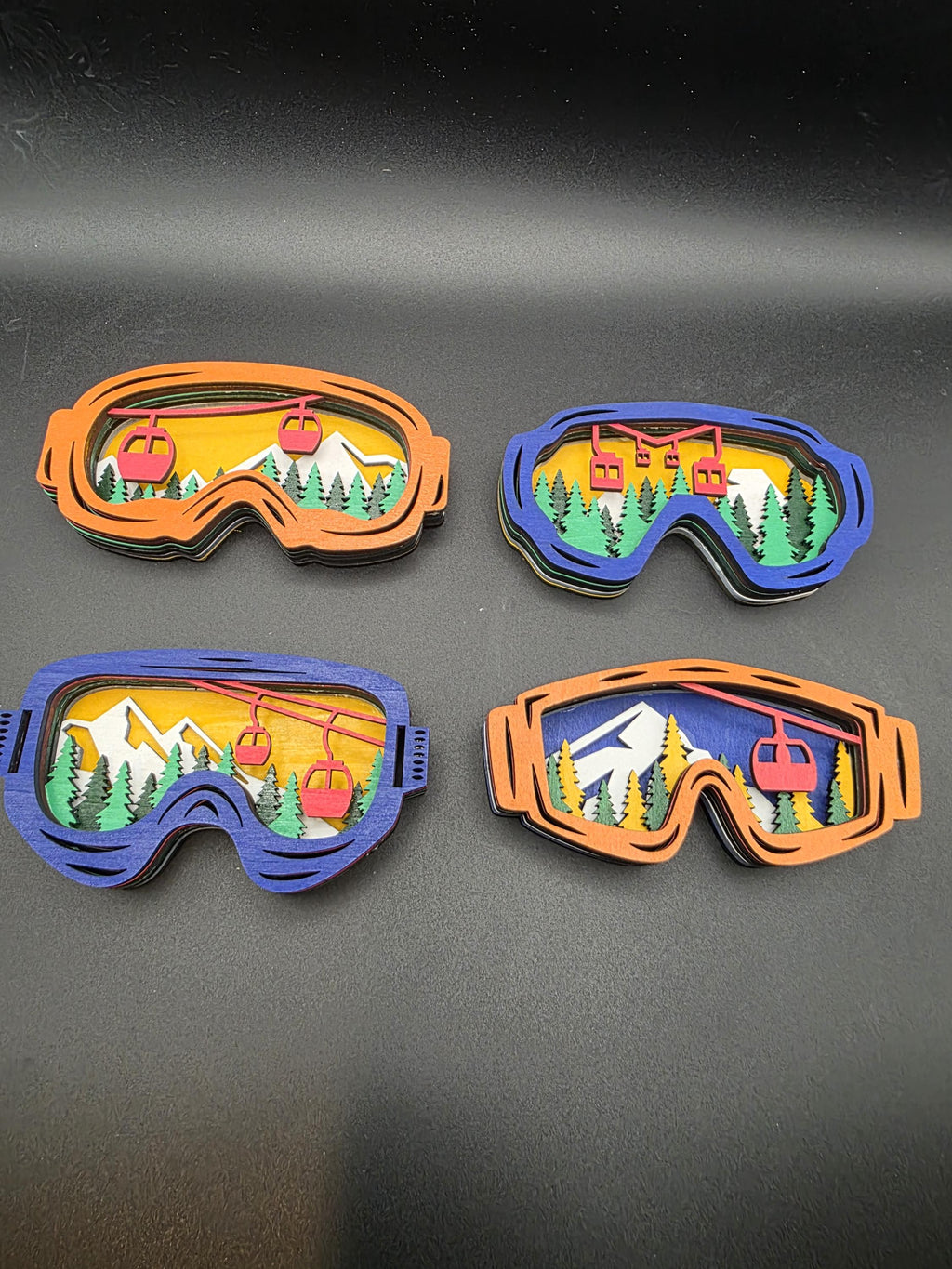 Four 3D wood ski lift wall art pieces in blue and orange frames with layered mountain scenes