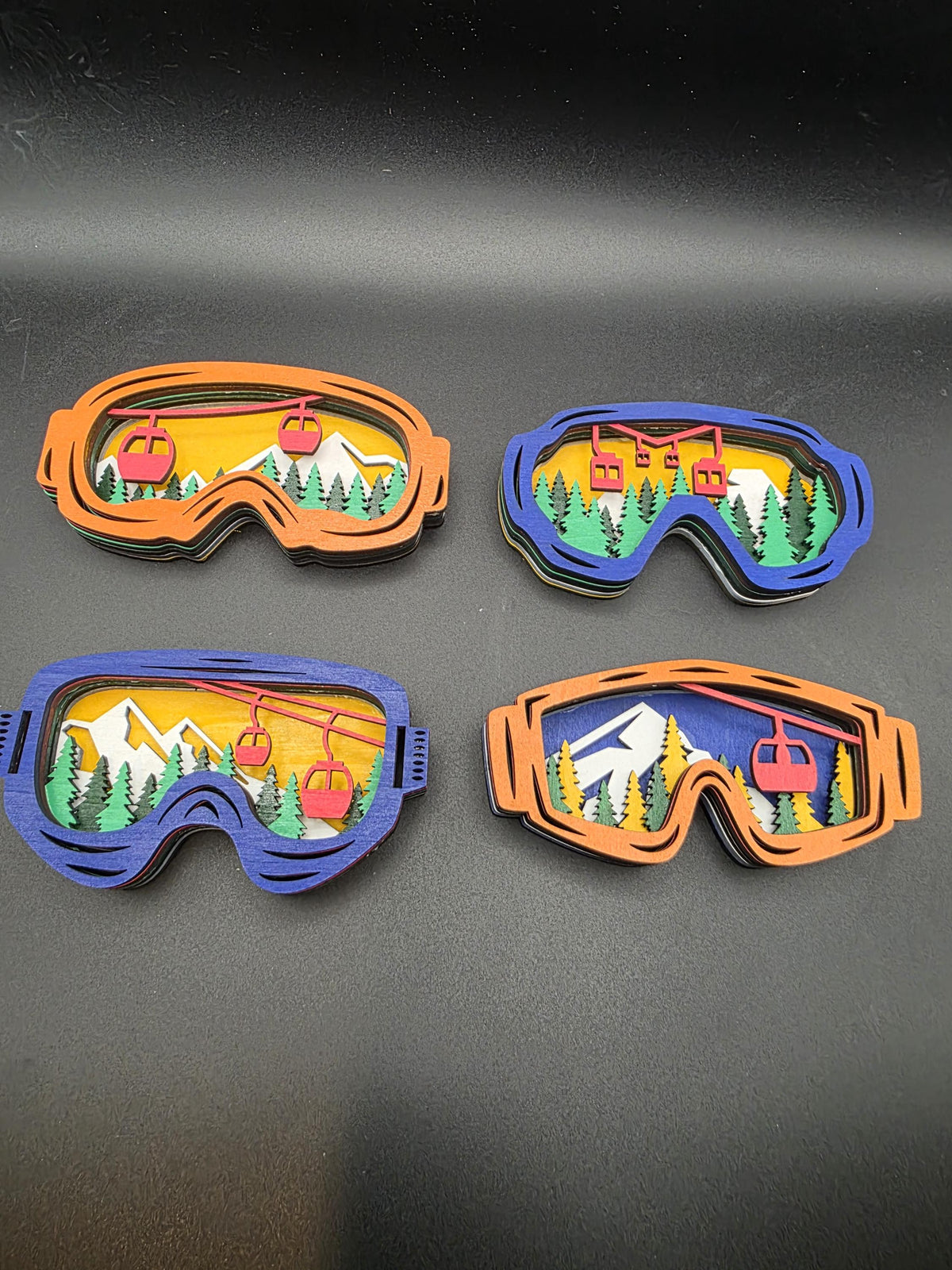 Four 3D wood ski lift wall art pieces in blue and orange frames with layered mountain scenes