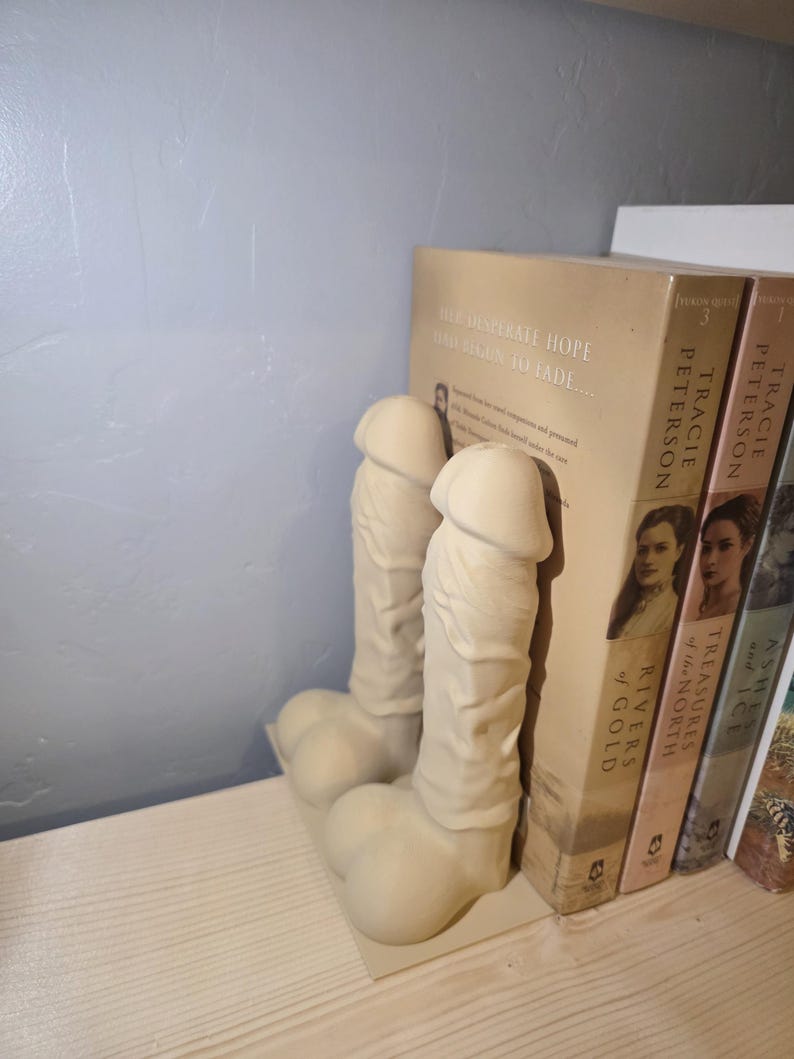 Beige Balls Deep penis bookends holding books on a shelf