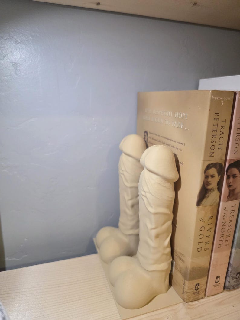 Beige Balls Deep penis bookends holding books, wide shelf view