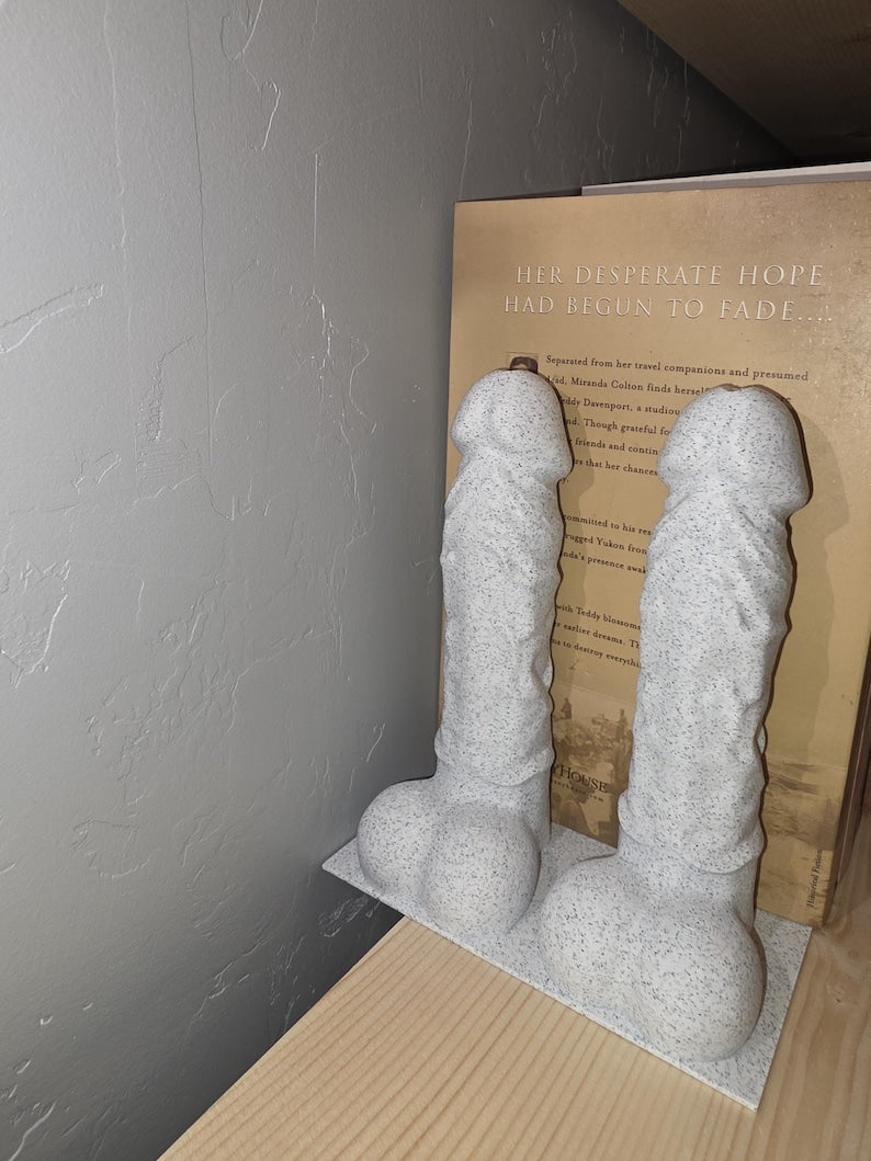 White Balls Deep penis bookends on a base plate holding a book, angled