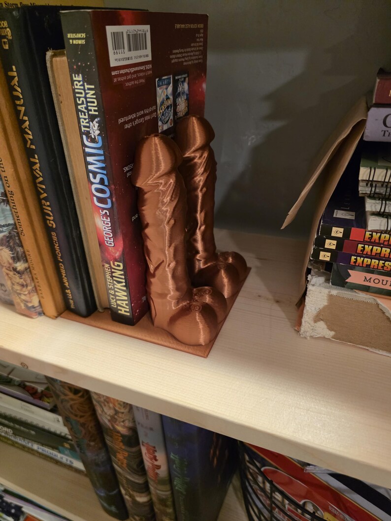 Copper Balls Deep penis bookends holding comics on a bookshelf