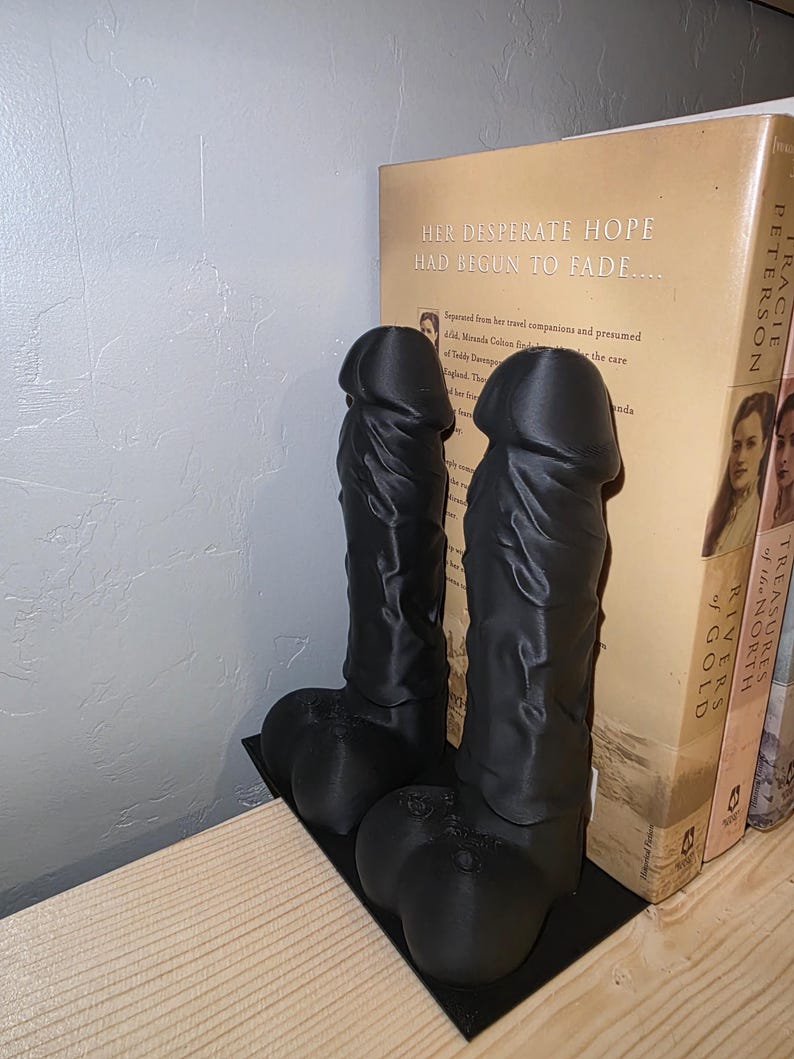 Black Balls Deep penis bookends holding books, side angle