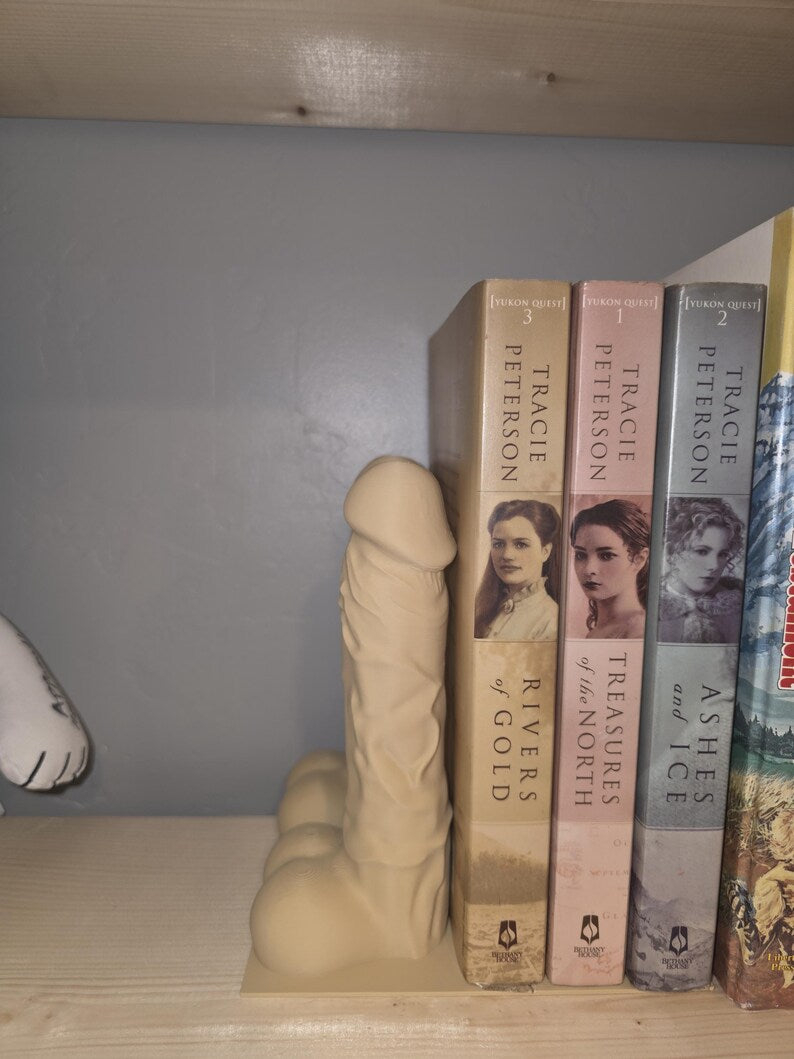 Single beige Balls Deep penis bookend holding paperback novels