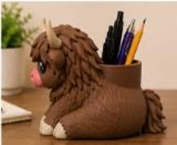 Hamish lying down with pens and pencils in the cup, side view