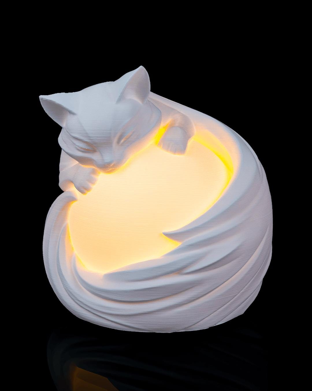 Feline sphere lamp lit, front view of the cat resting on the glowing orb