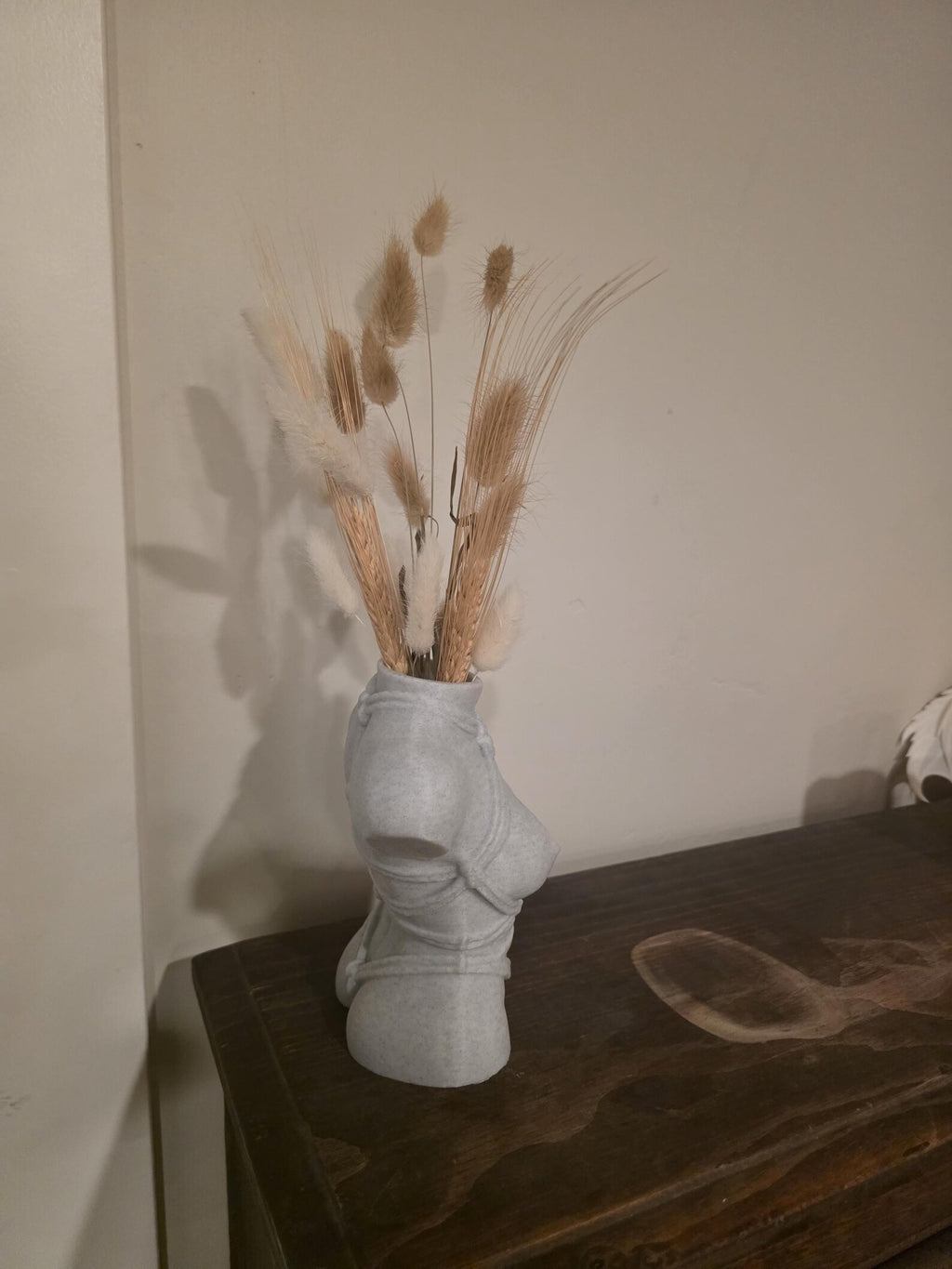 Light gray Knotty Girl vase, side profile on a dark table