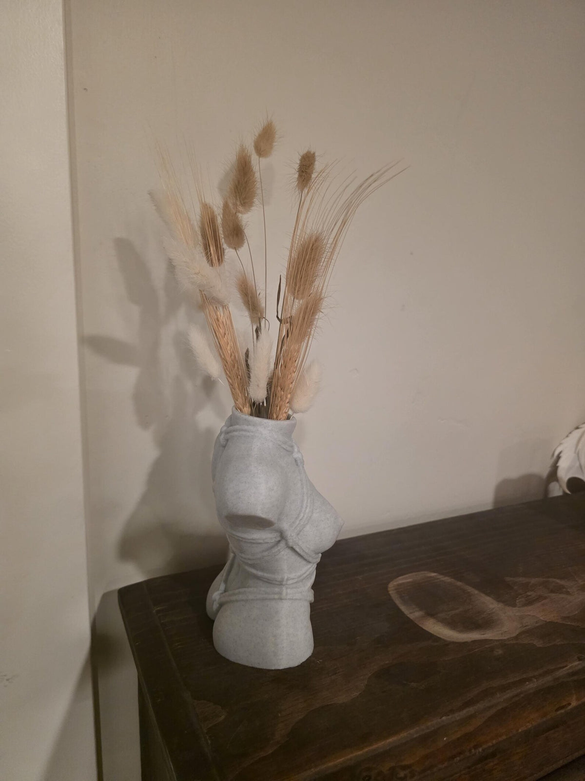 Light gray Knotty Girl vase, side profile on a dark table