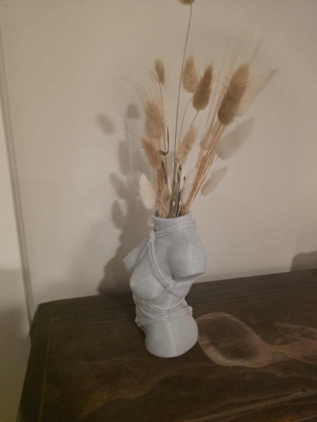 Light gray Knotty Girl vase, side view on a dark table