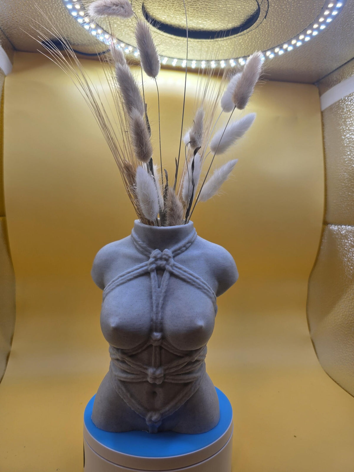 Gray Knotty Girl vase on a turntable with dried grasses, front view