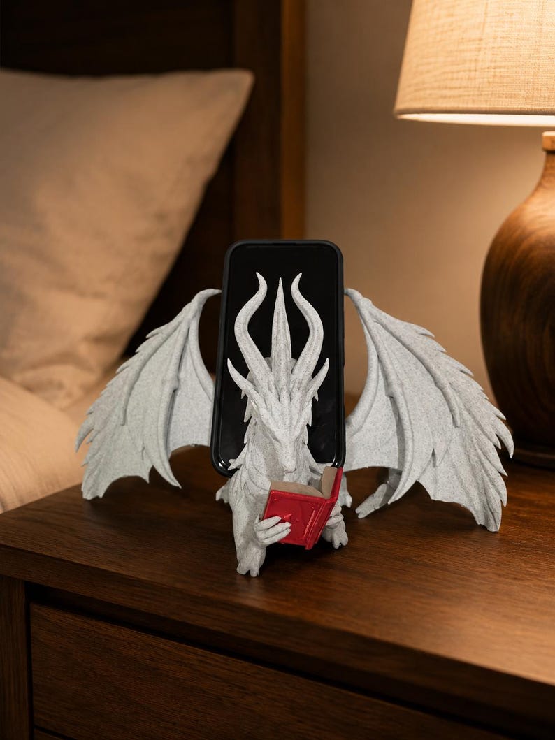 Moonplume dragon stand holding a phone on a nightstand, red mini book