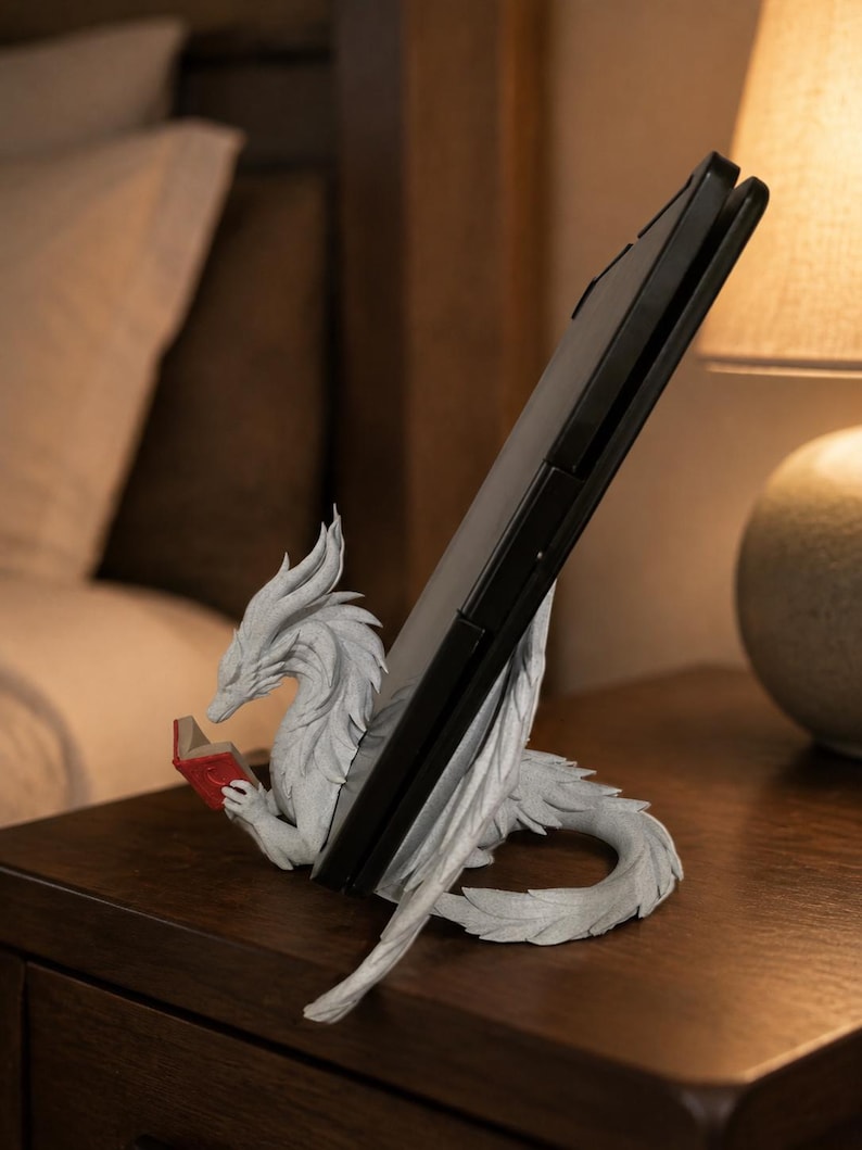 Side view of Moonplume holding an e-reader on a nightstand