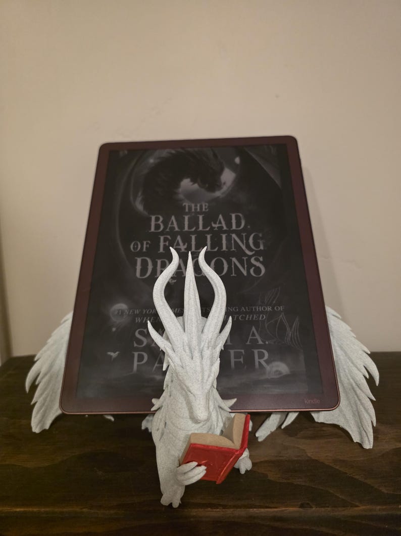 White Moonplume dragon holding an e-reader, red mini book, front view