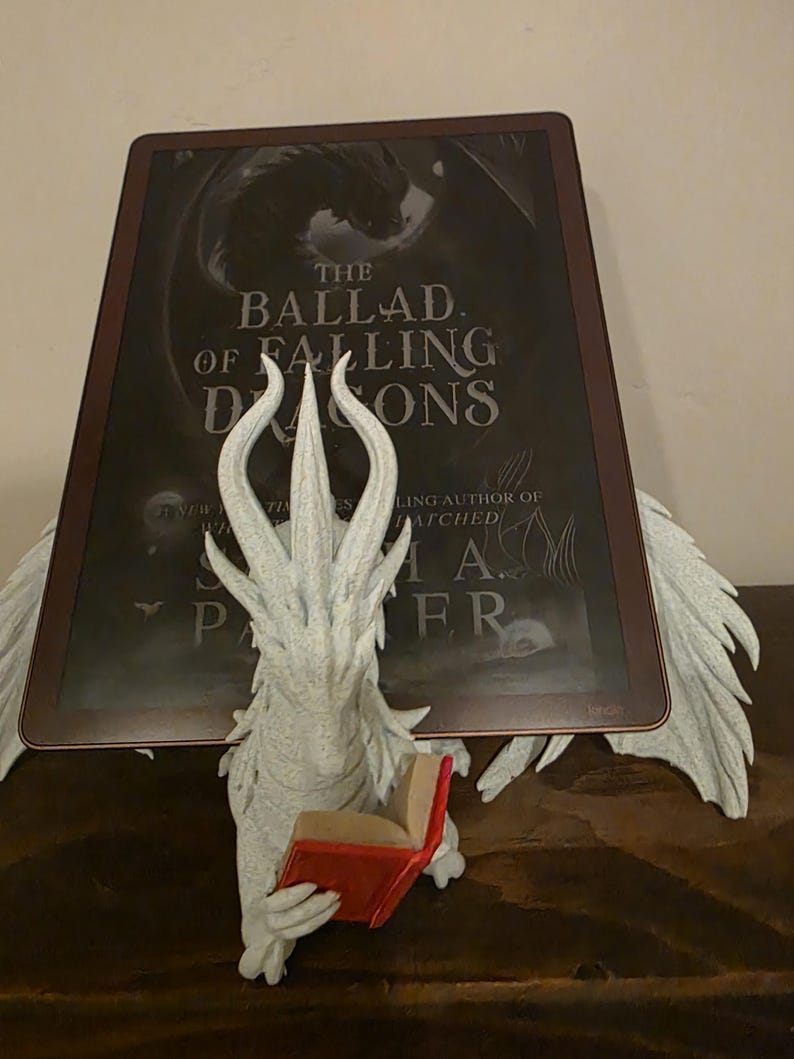 Moonplume holding an e-reader, close front view