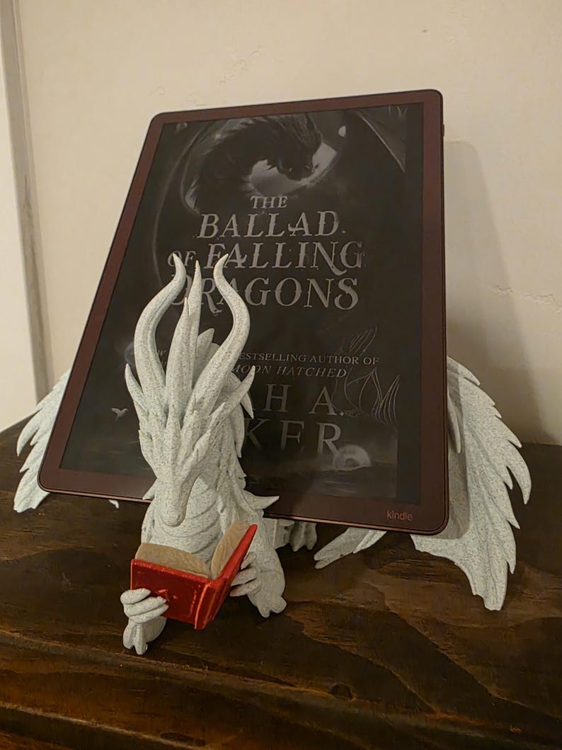 Moonplume dragon stand with an e-reader on a wood shelf