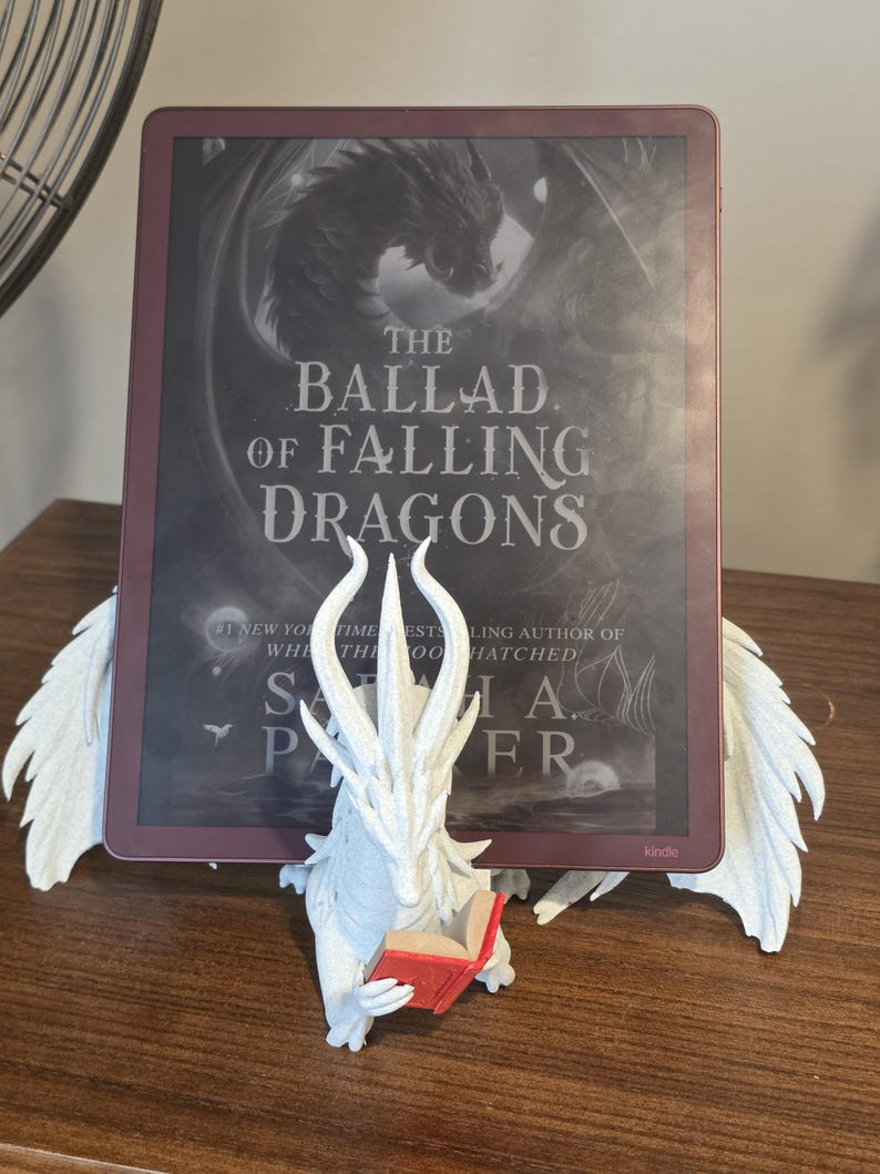 Moonplume with an e-reader and red mini book, straight-on view