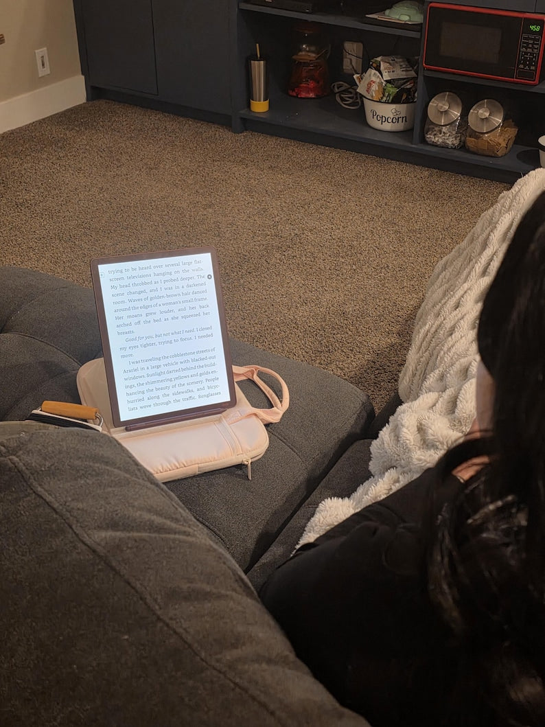 ReadRest holding an e-reader on a couch beside a reader